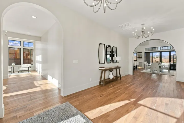 Light wood-finish flooring throughout, complemented by recessed lighting and multiple arched doorways