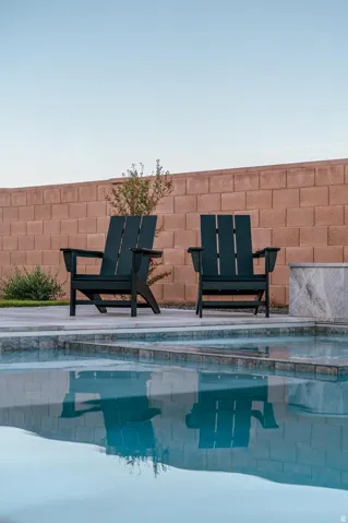 Swimming pool with stone coping and a concrete surround, enclosed by a block wall