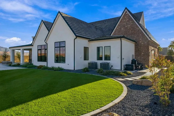 Stucco exterior with brick accents, multi-pane windows, covered patio, and a stone paver pathway