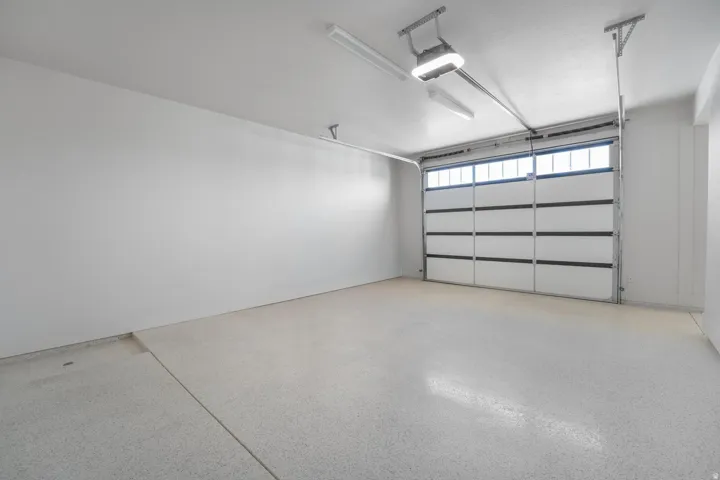 Garage featuring a panel-style door with upper window inserts, an automatic opener, and a finished floor