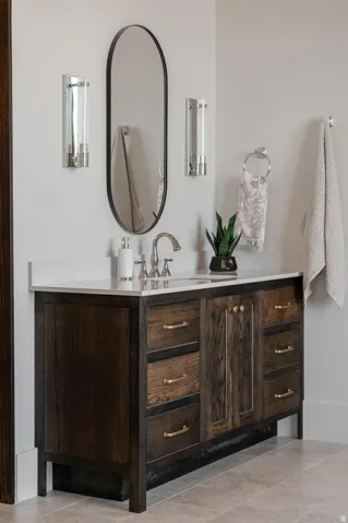 Dark wood-finish vanity with brass hardware, a white countertop, and an undermount sink