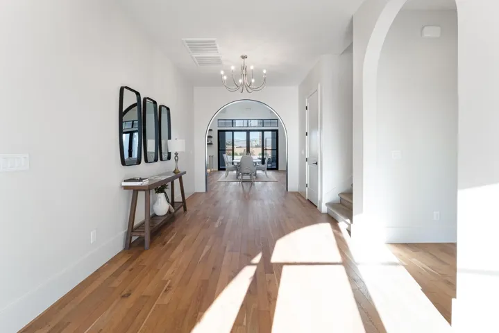 Wood-finish flooring throughout, arched doorways, a built-in chandelier, and white trim