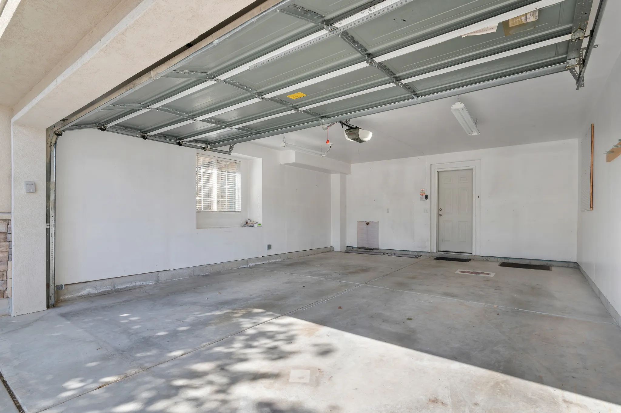 Two-car garage with concrete flooring, automatic garage door opener, and a window