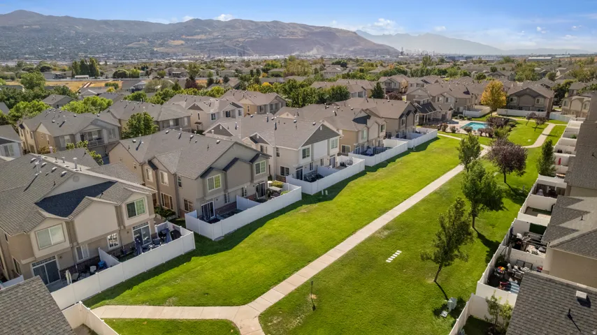 Aerial View of community with green spaces with paved walkways, mature trees, and a community swimming pool