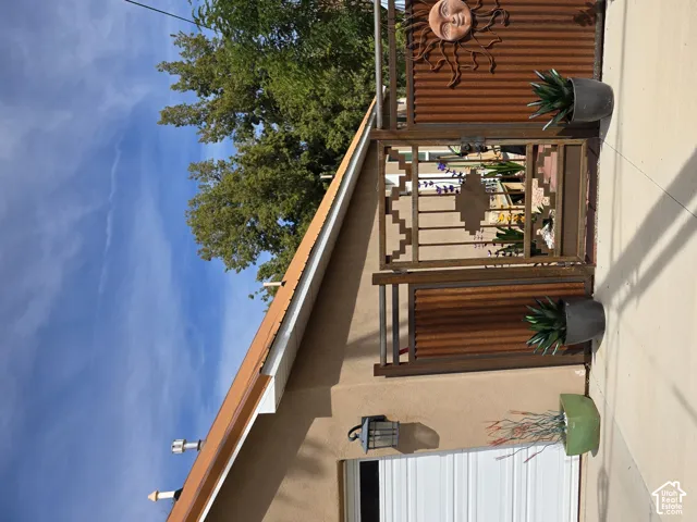 Enclosed courtyard with a decorative metal gate, corrugated metal privacy fence, and concrete paving
