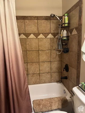 Tub and shower combination featuring a bronze fixture, tiled walls, and a decorative tile accent band