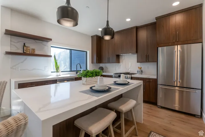 Kitchen with wood-finish cabinetry, stainless steel appliances, white countertops, and light wood-finish flooring