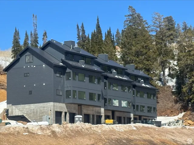 Contemporary multi-level residence featuring dark vertical siding and a black sloped roof
