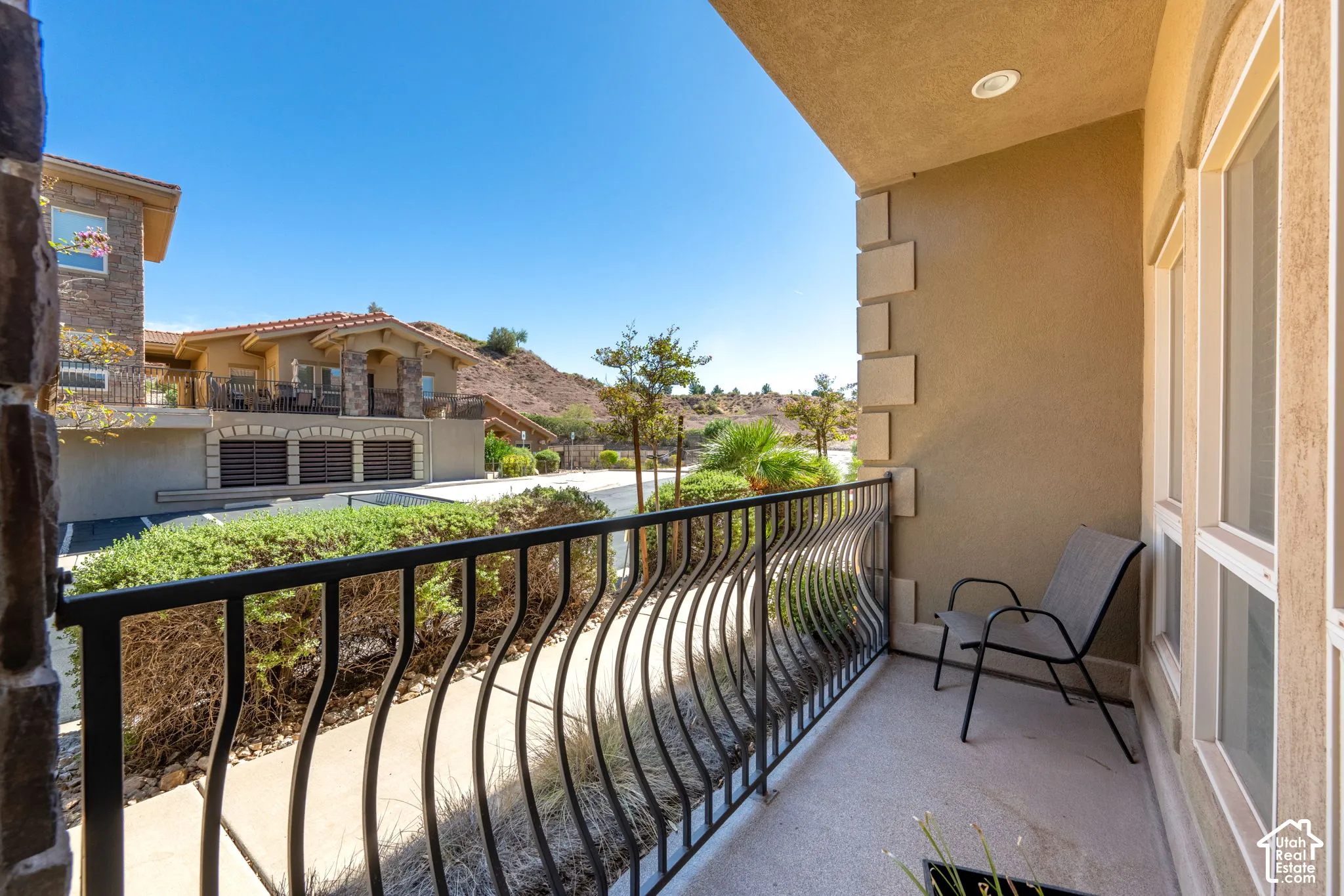 Private balcony with a decorative wrought iron railing, stucco exterior, and multi-pane windows