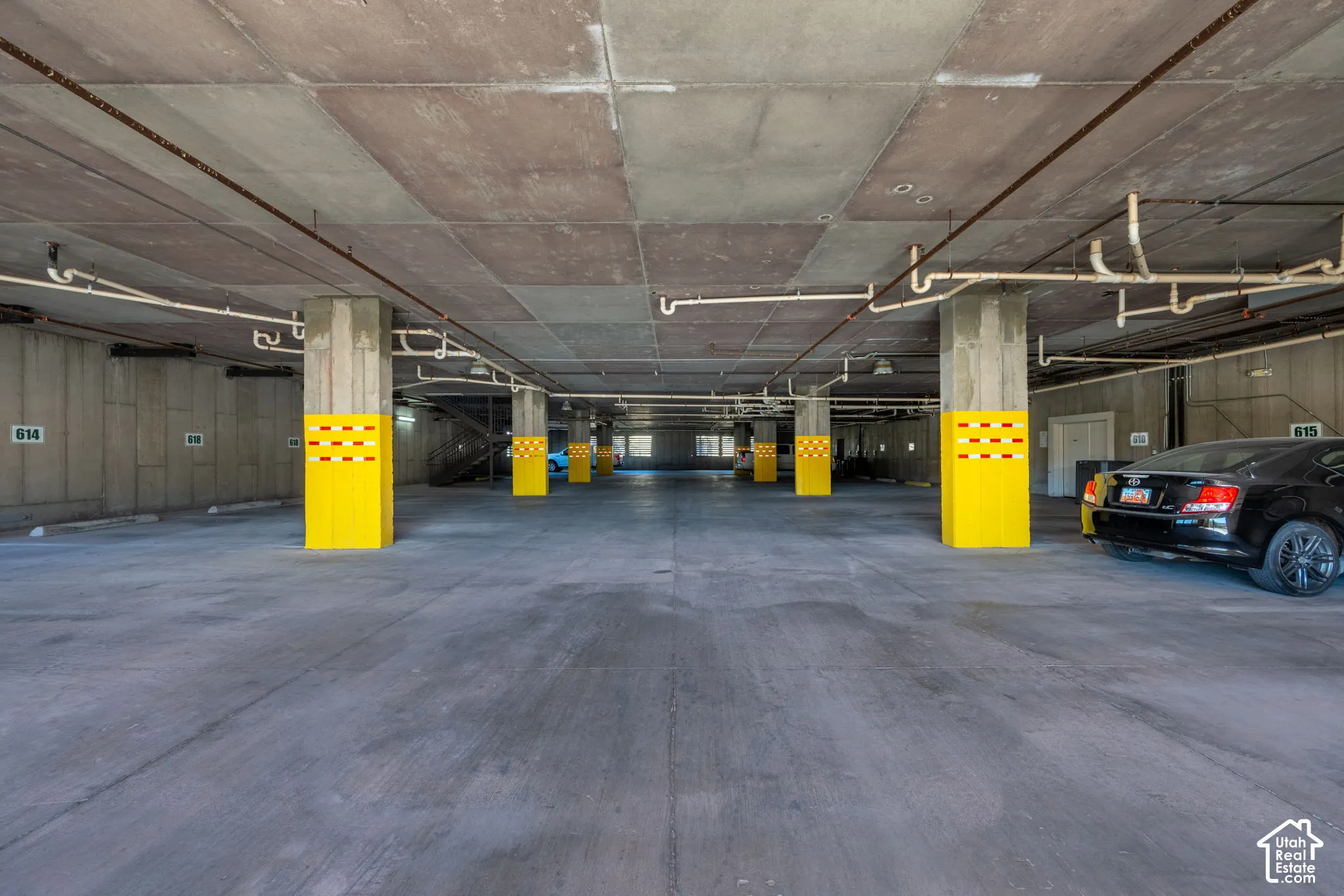 Concrete parking structure with exposed piping and yellow-painted support columns