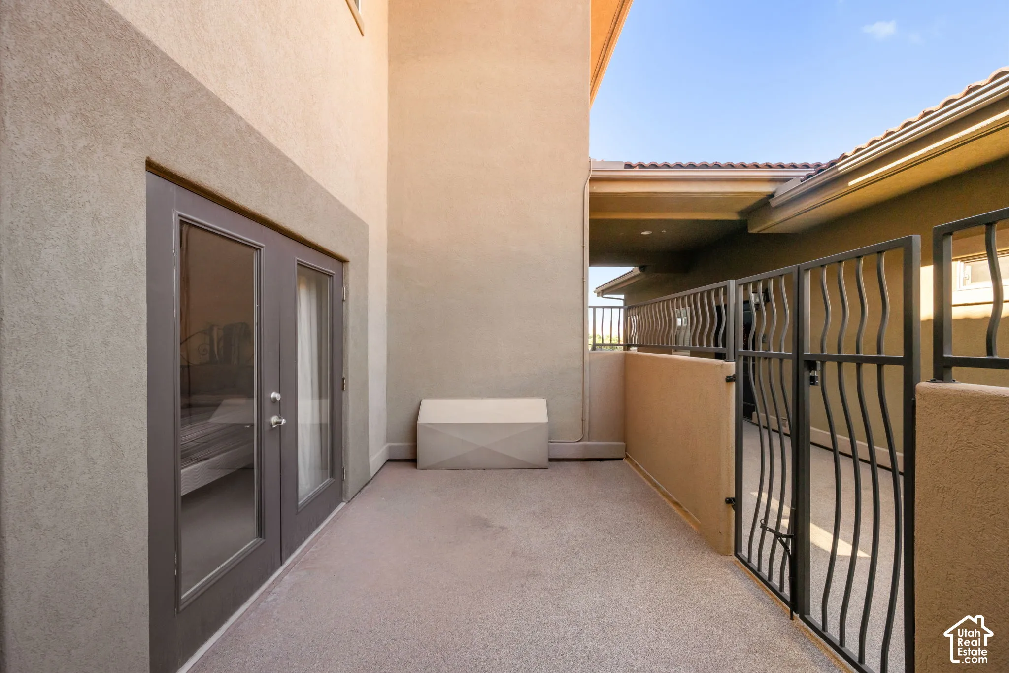 Private outdoor patio featuring textured stucco walls, double glass-paneled doors, and a decorative wrought iron gate