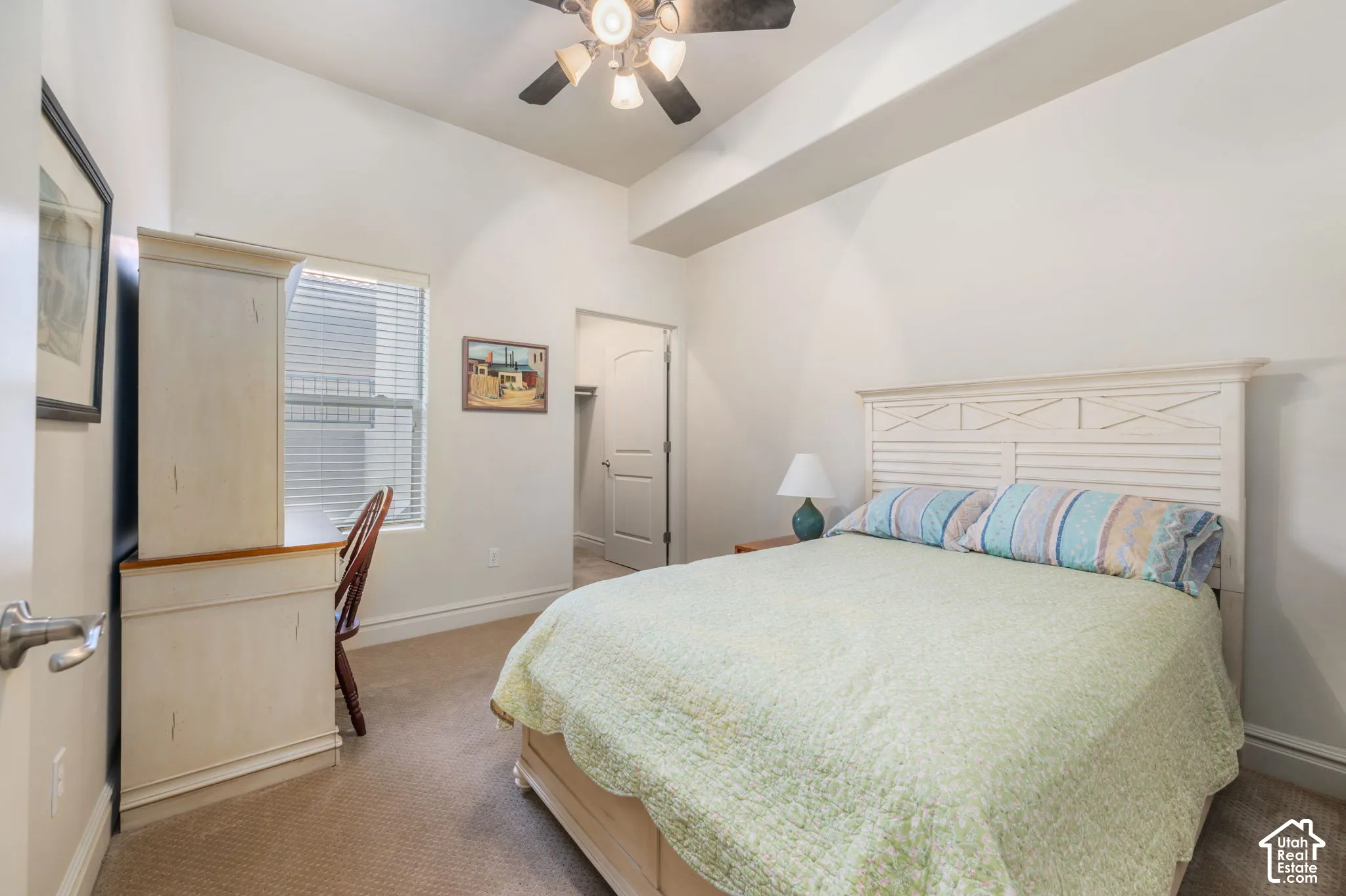 Carpeted flooring, window with blinds, built-in desk, paneled door, and ceiling fan