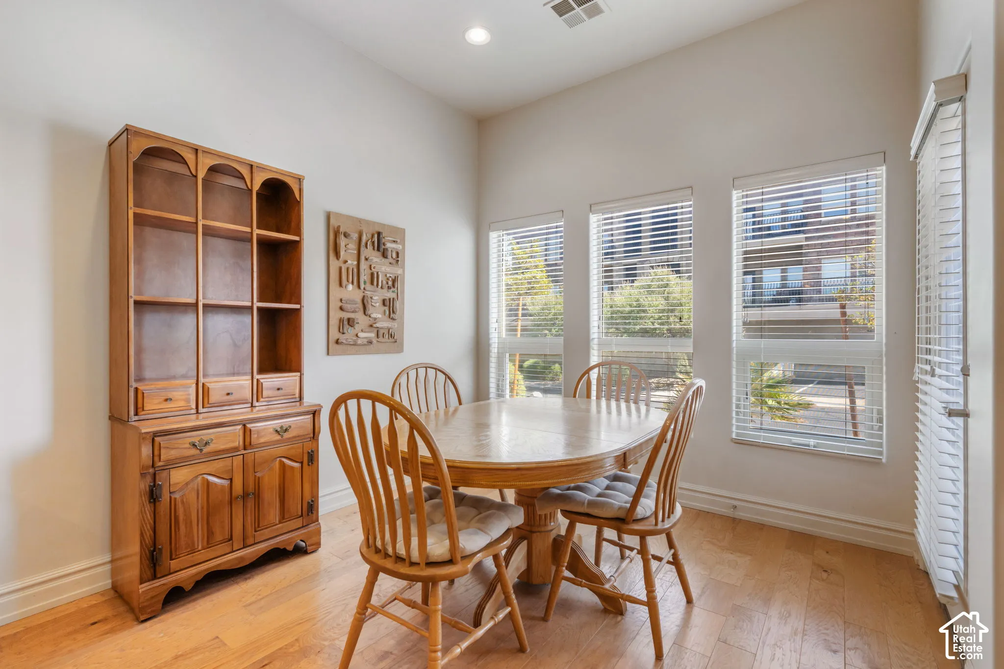Wood-finish flooring, recessed lighting, and multiple windows with horizontal blinds