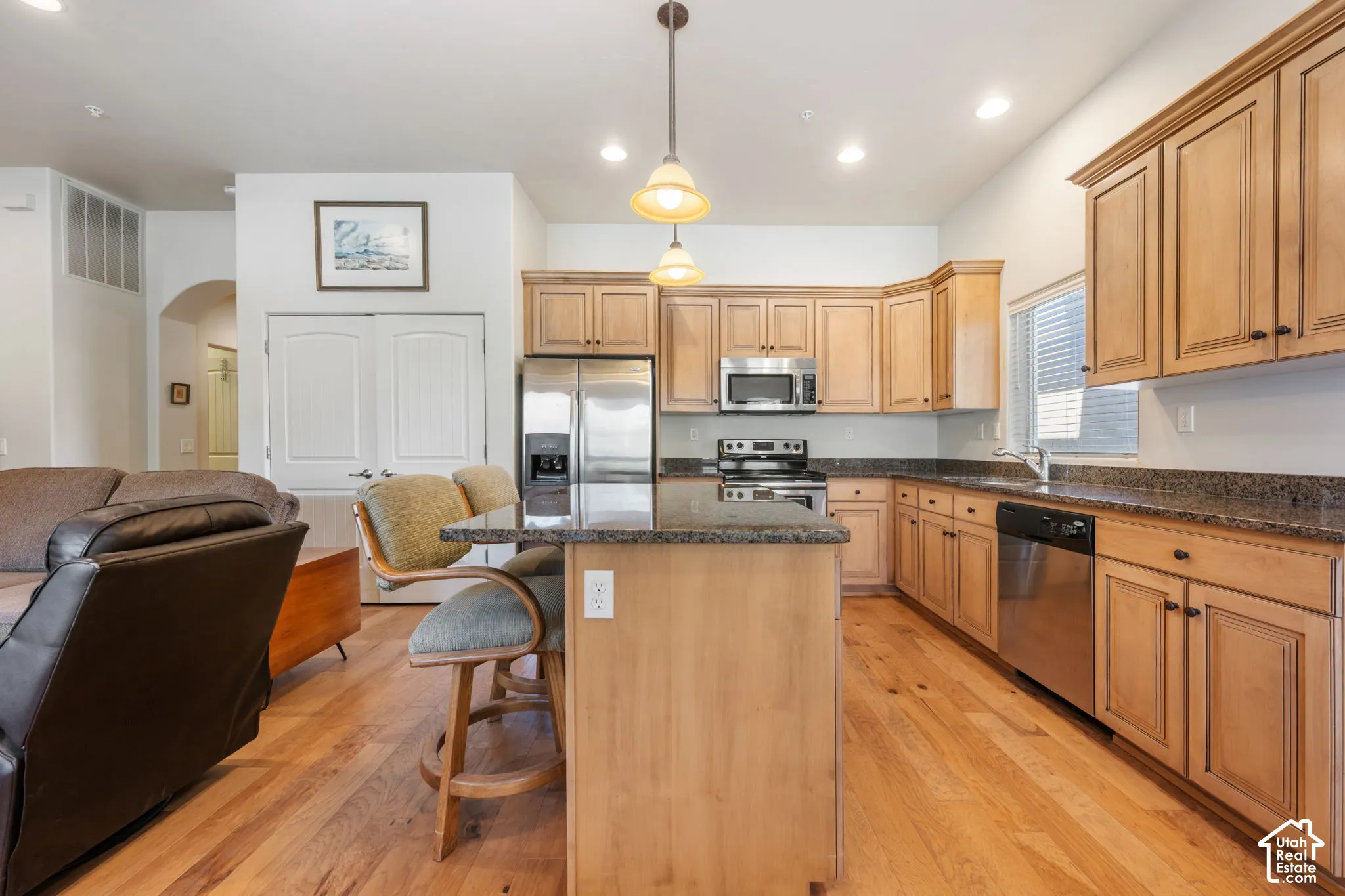 Kitchen featuring wood-finish cabinetry, stainless steel appliances, granite countertops, and wood-finish flooring