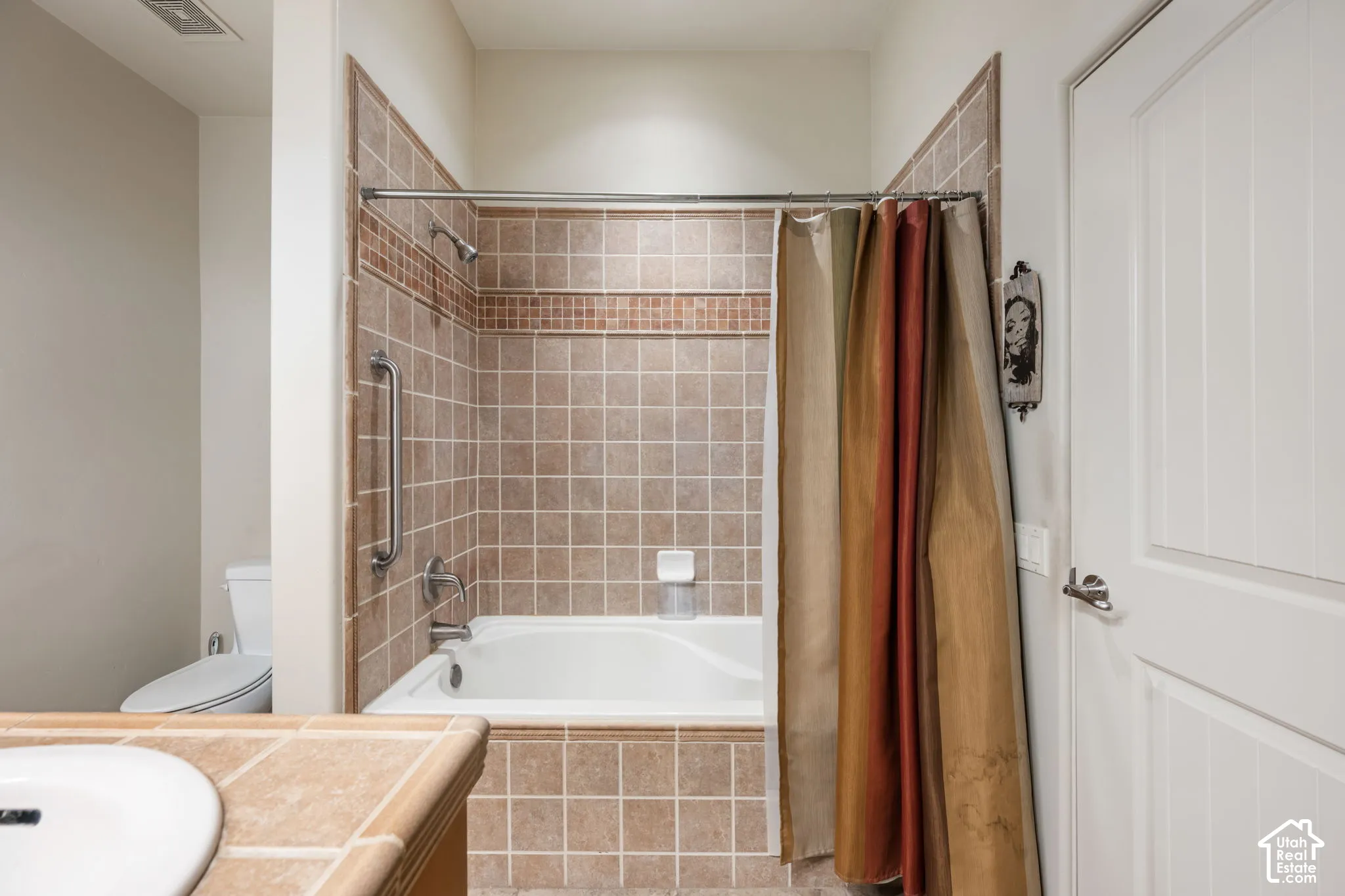 Bathtub with tiled surround, integrated grab bar, and a single showerhead
