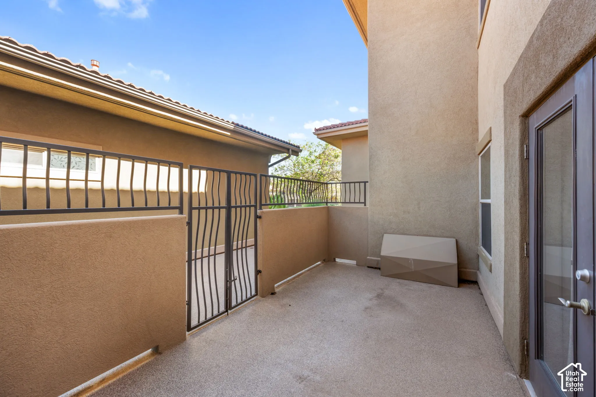 Stucco exterior with tile roofing, a private patio, and a secure wrought iron gate