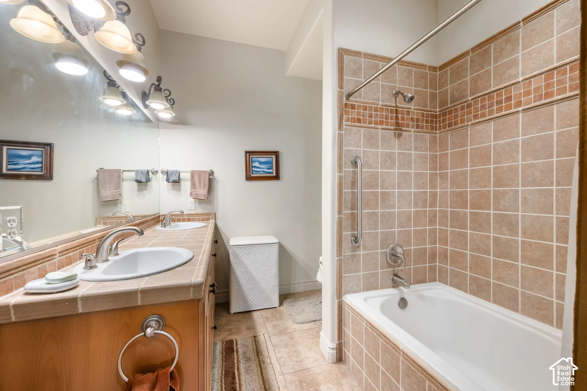 Double vanity with tile countertop, wood-finish cabinetry, and brushed nickel fixtures