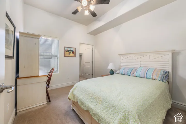 Carpeted flooring, window with blinds, built-in desk, paneled door, and ceiling fan