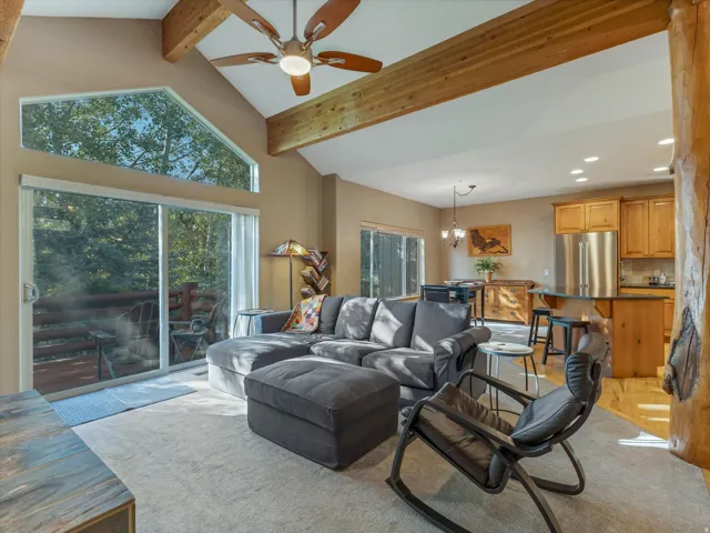 Vaulted ceilings with exposed wood beams, expansive glass sliding doors, and a triangular transom window
