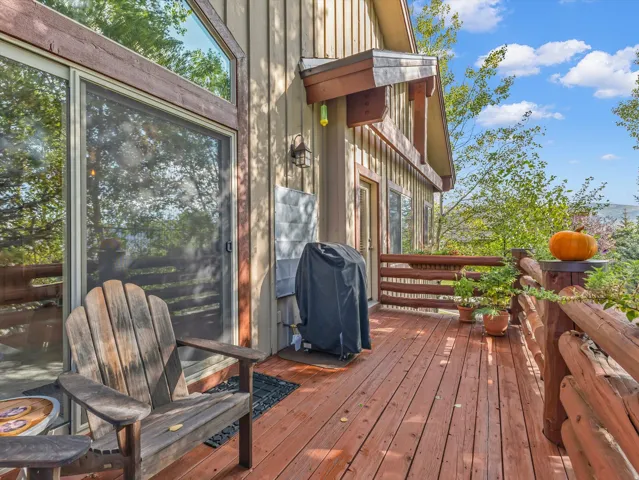 Expansive wood deck with log railing, vertical wood siding, large sliding glass door, and transom window