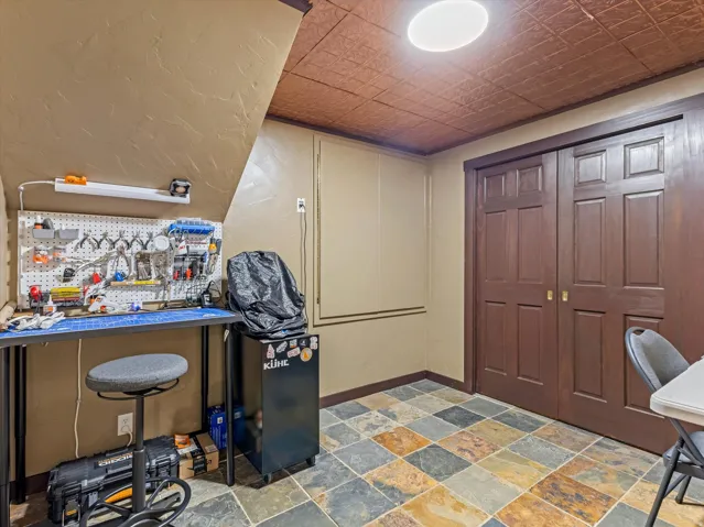 Multi-toned slate tile flooring, brown paneled bi-fold doors, and a textured ceiling with a flush-mount light fixture
