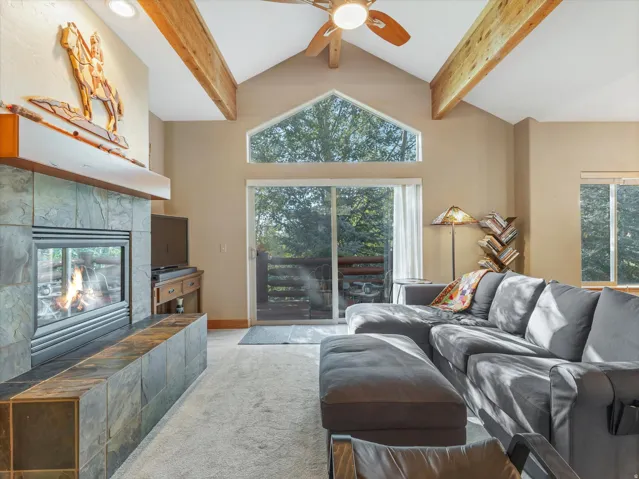 Varnished wood ceiling beams, vaulted ceilings, and a slate-tiled fireplace with hearth