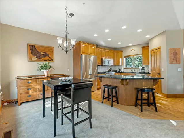Kitchen featuring wood cabinetry, stainless steel appliances, an island with seating, recessed lighting, and wood-finish flooring