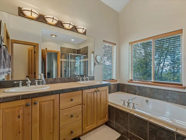 Dual vanity with undermount sinks, wood cabinetry, and a large soaking tub