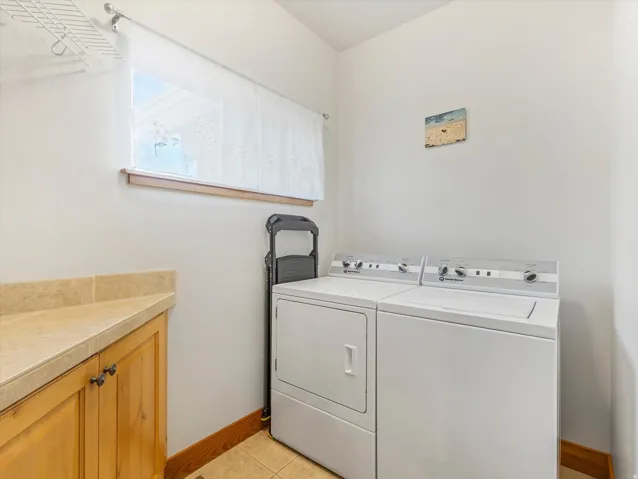 Built-in cabinetry with a light-toned countertop, tile flooring, and a window with trim