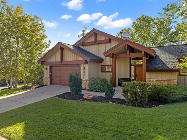 Stone veneer and siding exterior, gabled rooflines, covered entry with wood beams, attached garage, concrete driveway