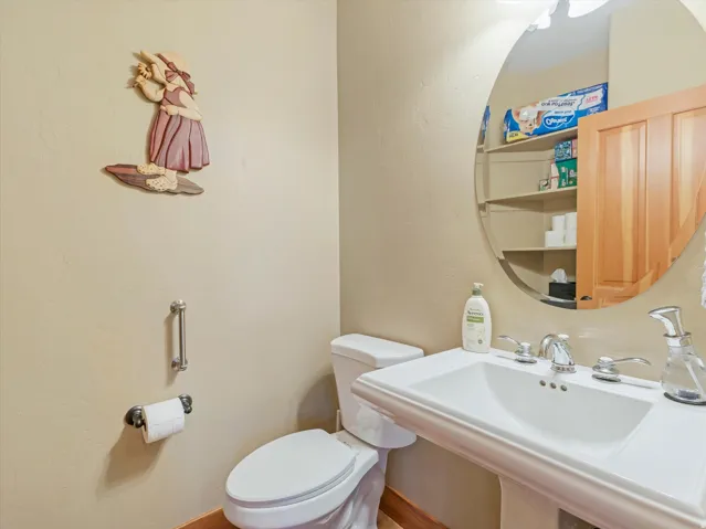 Pedestal sink with chrome fixtures, wall-mounted mirror, and built-in shelving