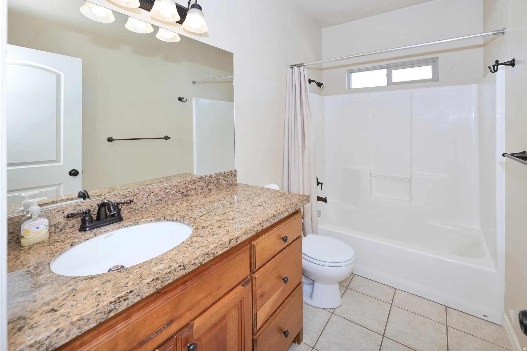 Vanity with a granite-style countertop, wood-finish cabinetry, and an oval undermount sink