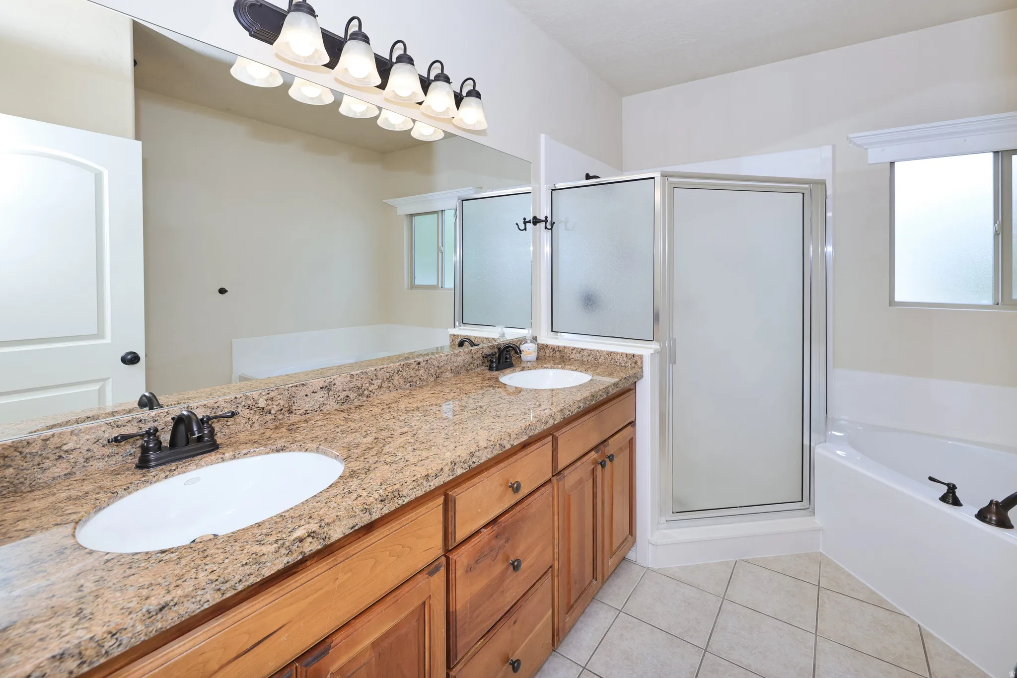 Dual vanity with wood cabinetry and stone-finish countertop