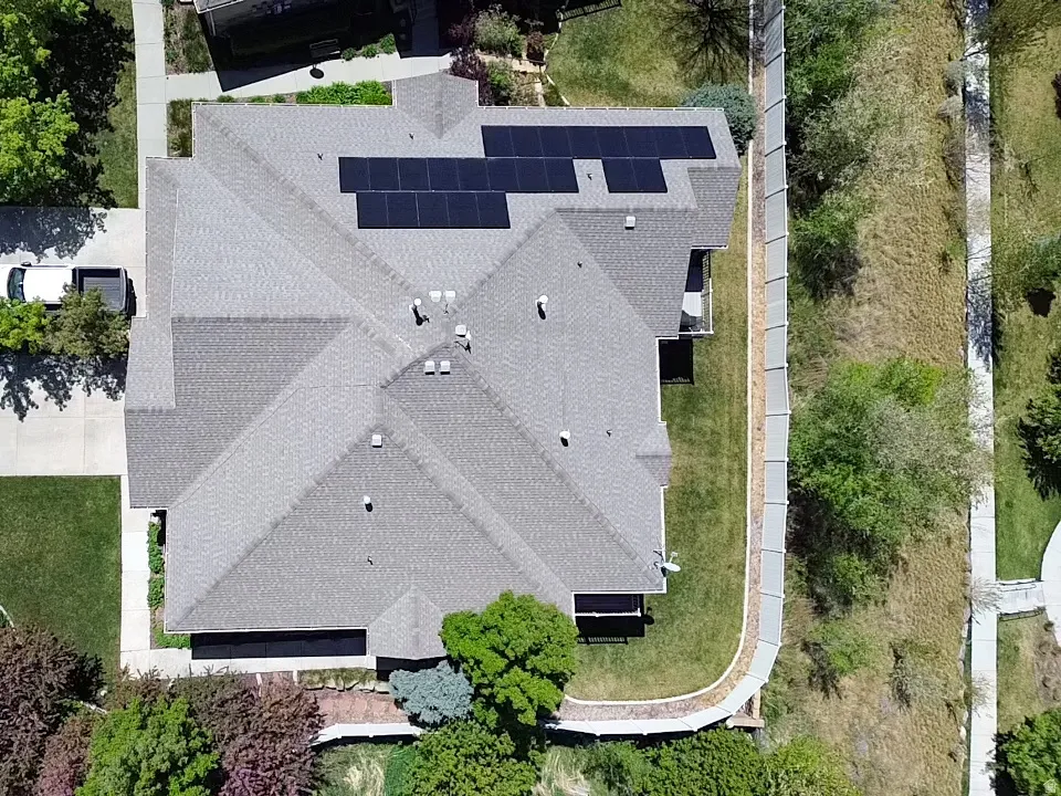 Gable roof with solar panel array, concrete driveway, and mature landscaping