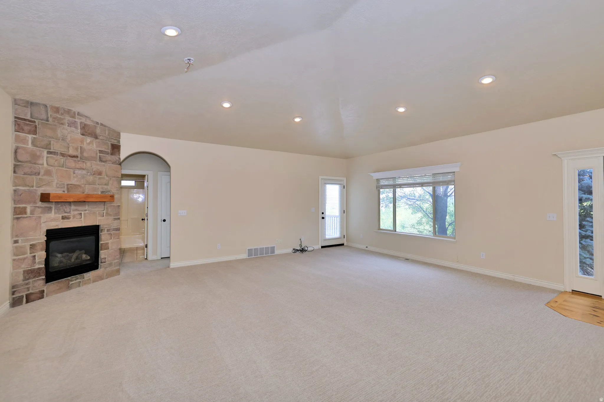Stone-clad corner fireplace with a wood-finish mantel and a gas insert