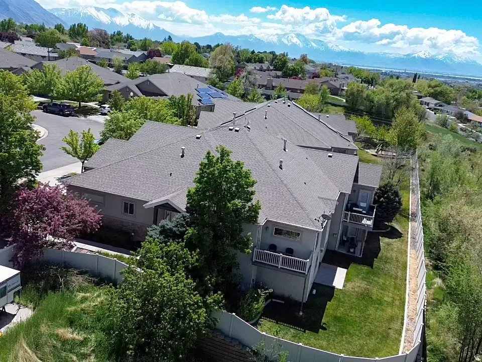 Property featuring a multi-level design, multiple balconies, a fenced perimeter, and a manicured lawn