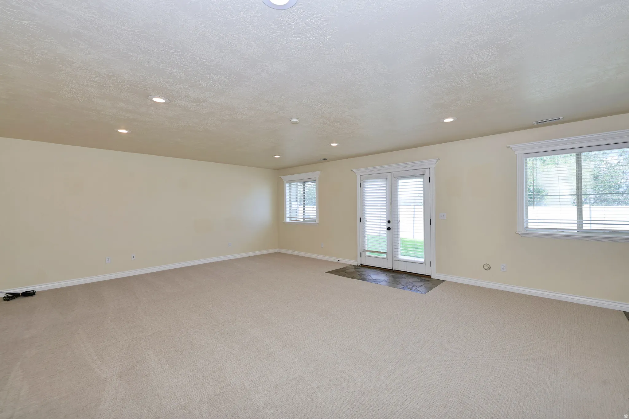 Recessed lighting, light-toned carpeting, dual pane windows, French doors, and neutral wall paint