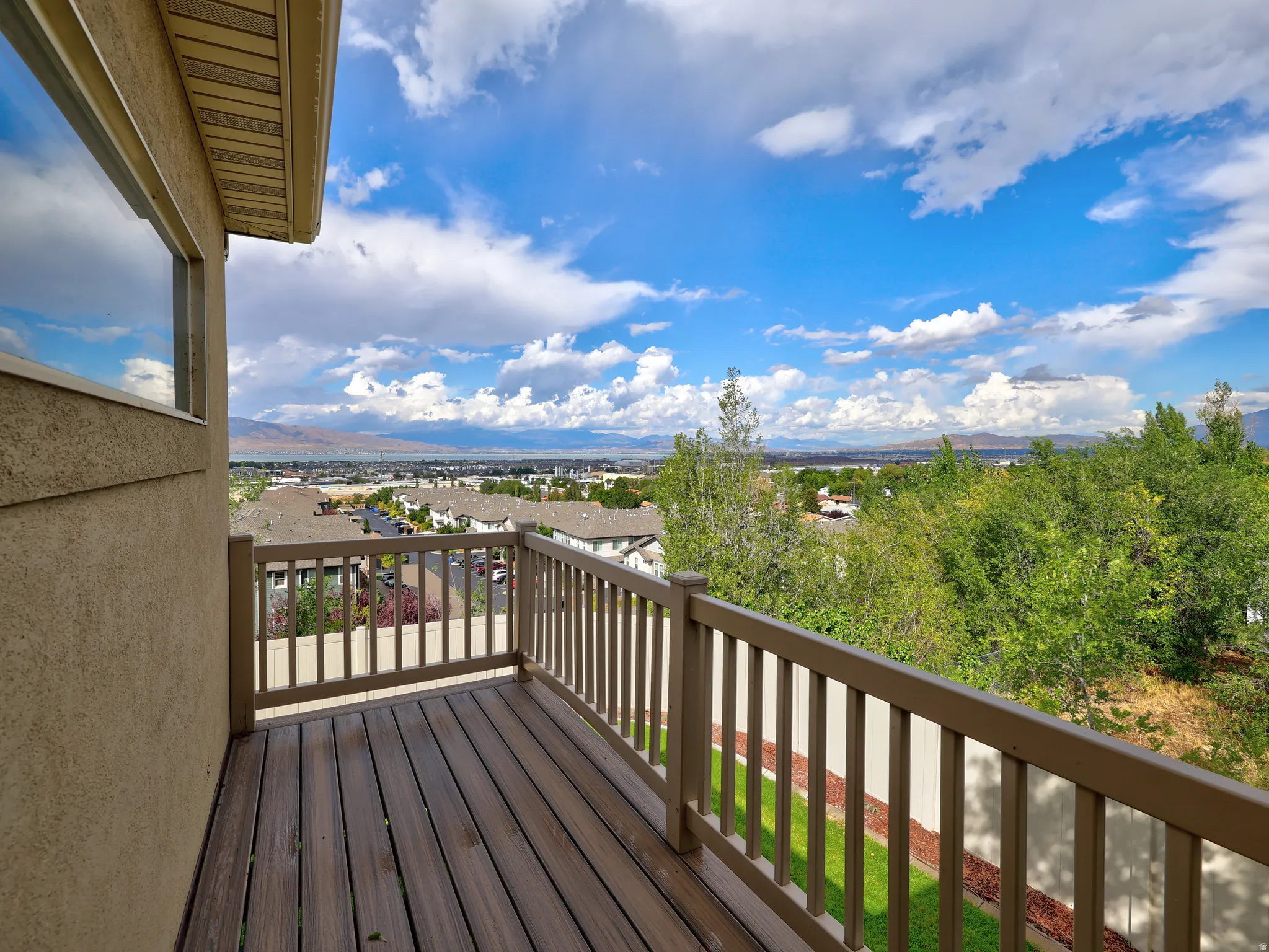 Balcony with composite decking and railing, offering a distant mountain and city backdrop