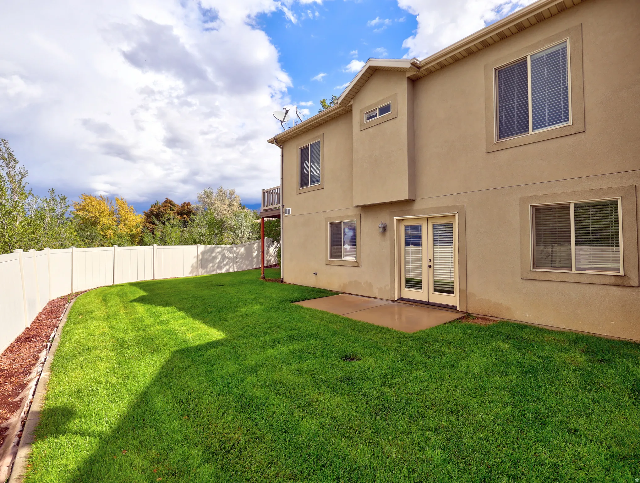 Expansive backyard with a manicured lawn, full-height privacy fencing, and a concrete patio