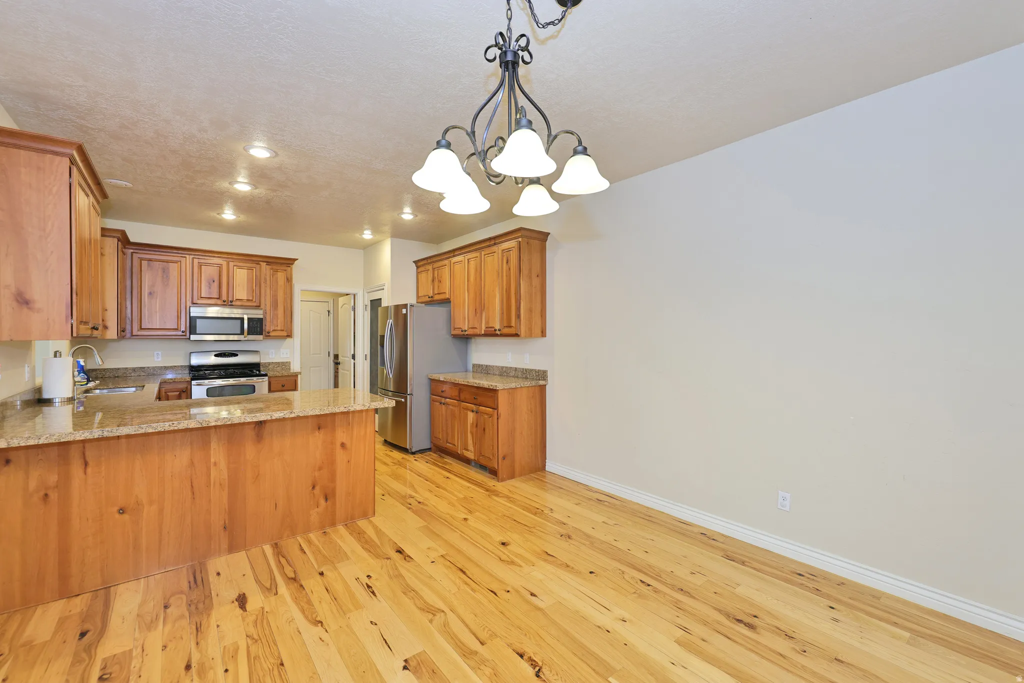 Kitchen with wood-finish flooring, recessed lighting, and a chandelier