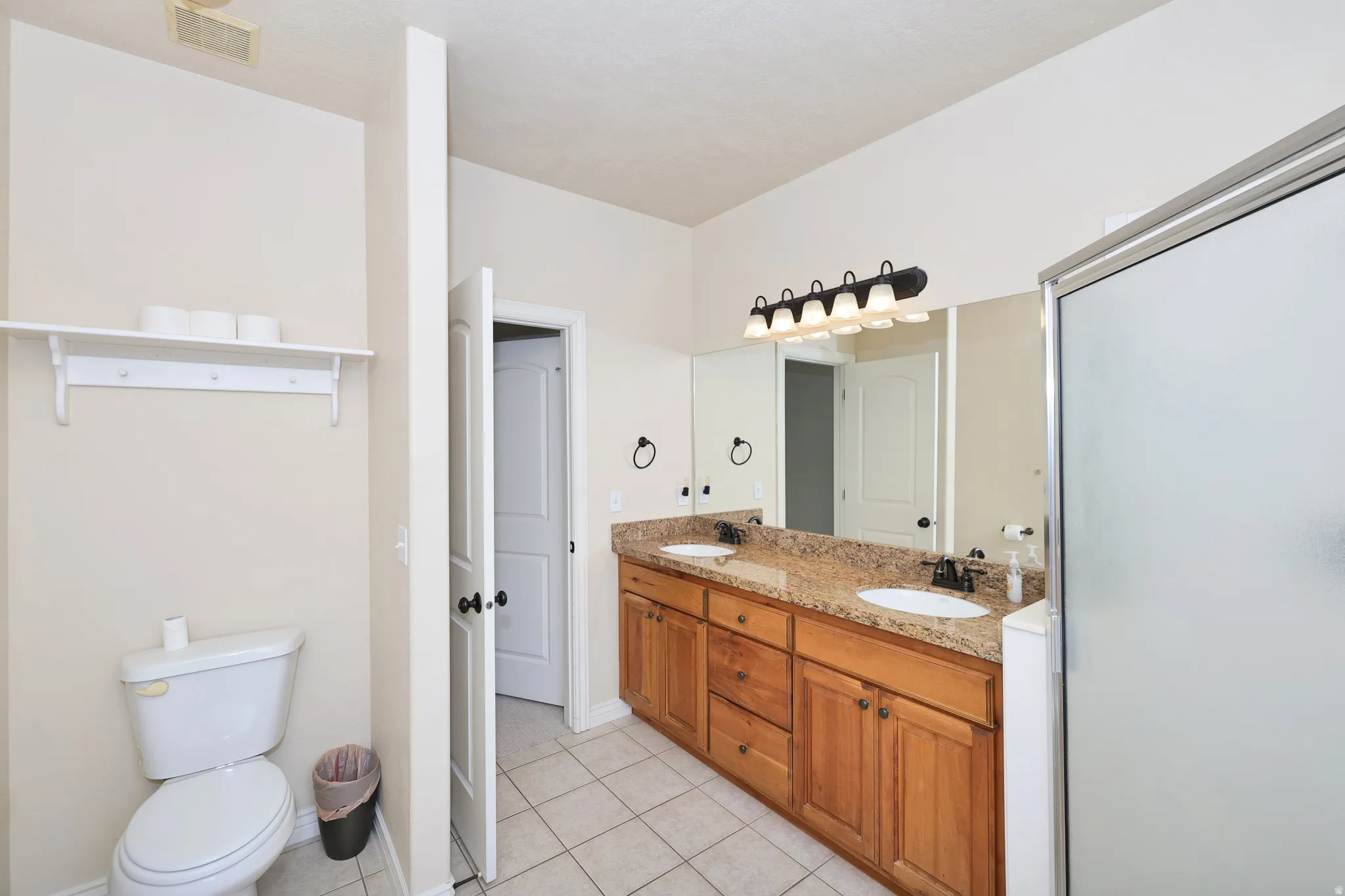 Dual vanity with undermount sinks, granite-style countertop, and wood-finish cabinetry