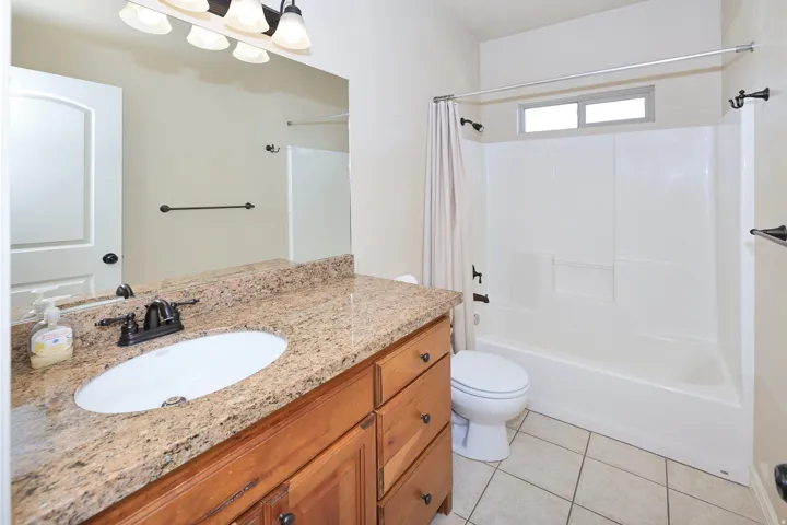 Vanity with a granite-style countertop, wood-finish cabinetry, and an oval undermount sink