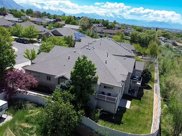 Property featuring a multi-level design, multiple balconies, a fenced perimeter, and a manicured lawn