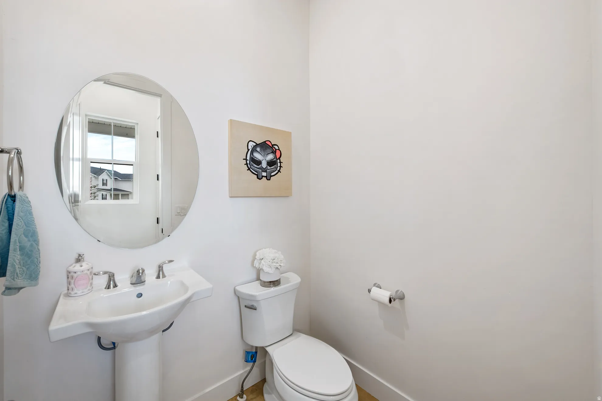 Pedestal sink with chrome fixtures, circular wall-mounted mirror, and white toilet