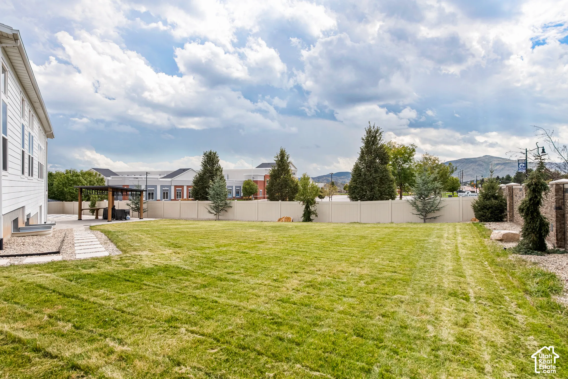 Expansive backyard with a lush lawn, privacy fencing, and a built-in pergola