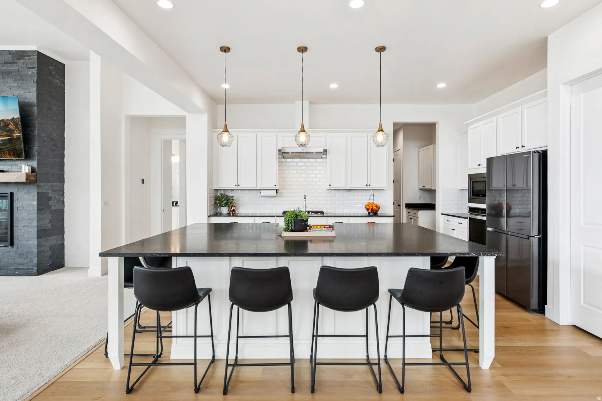 Expansive kitchen island with a dark countertop, white cabinetry, and pendant lighting