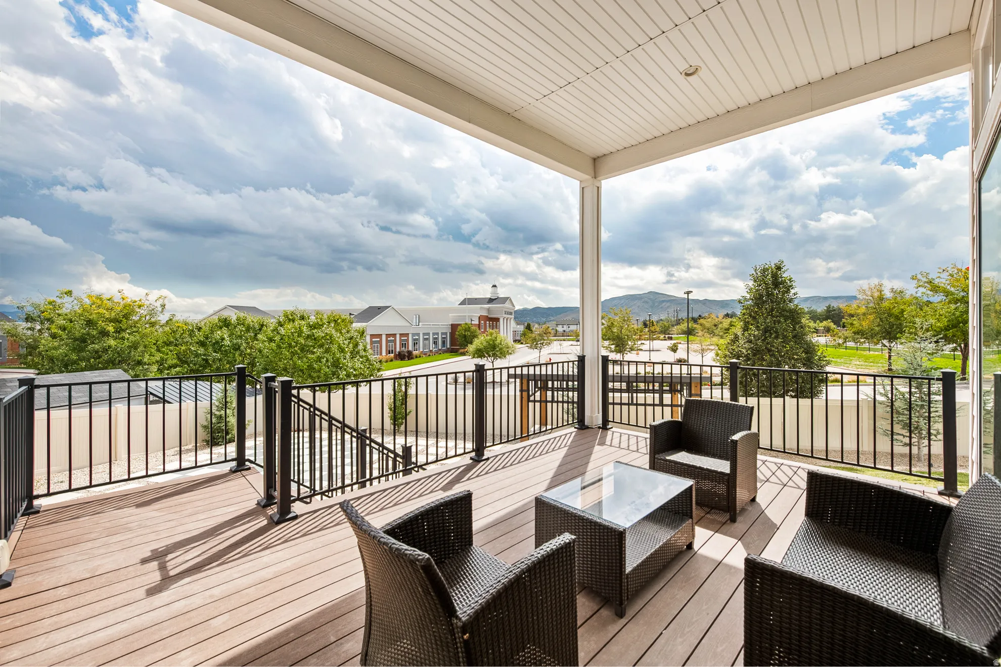 Expansive covered balcony featuring composite decking, black metal railings, and a white paneled ceiling