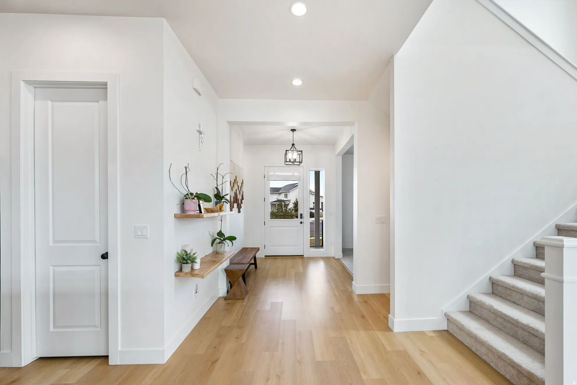 Light wood-finish flooring, recessed ceiling lighting, and a front entry door with side lites and transom