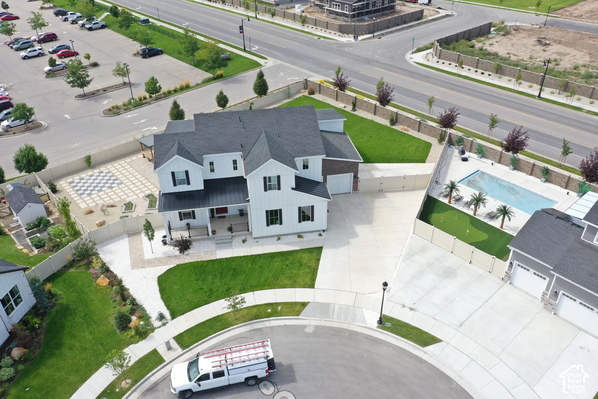 Expansive property featuring a large in-ground swimming pool, adjacent putting green, and a checkered patio area