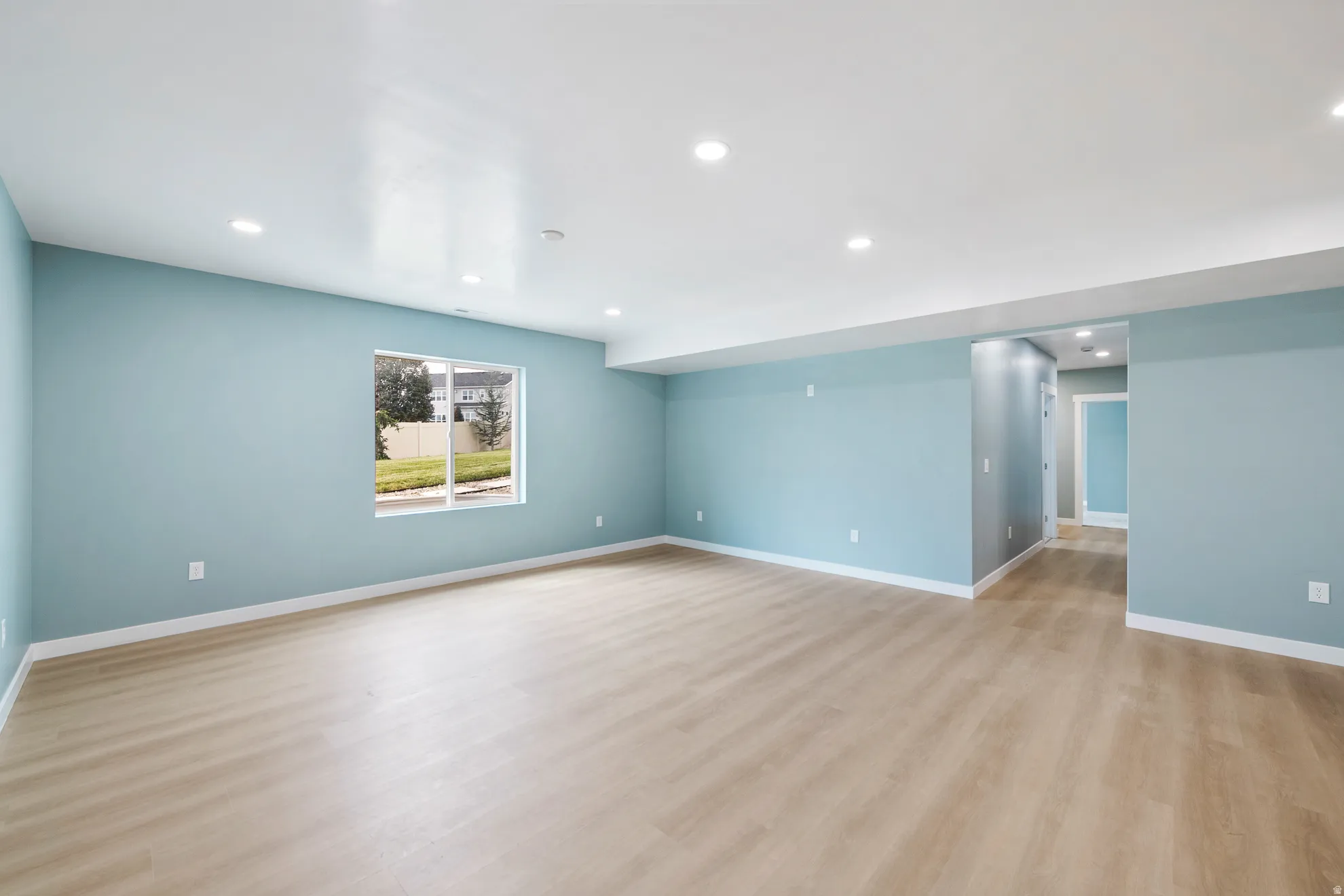 Spacious interior with wood-finish flooring, recessed lighting, and a neutral color palette